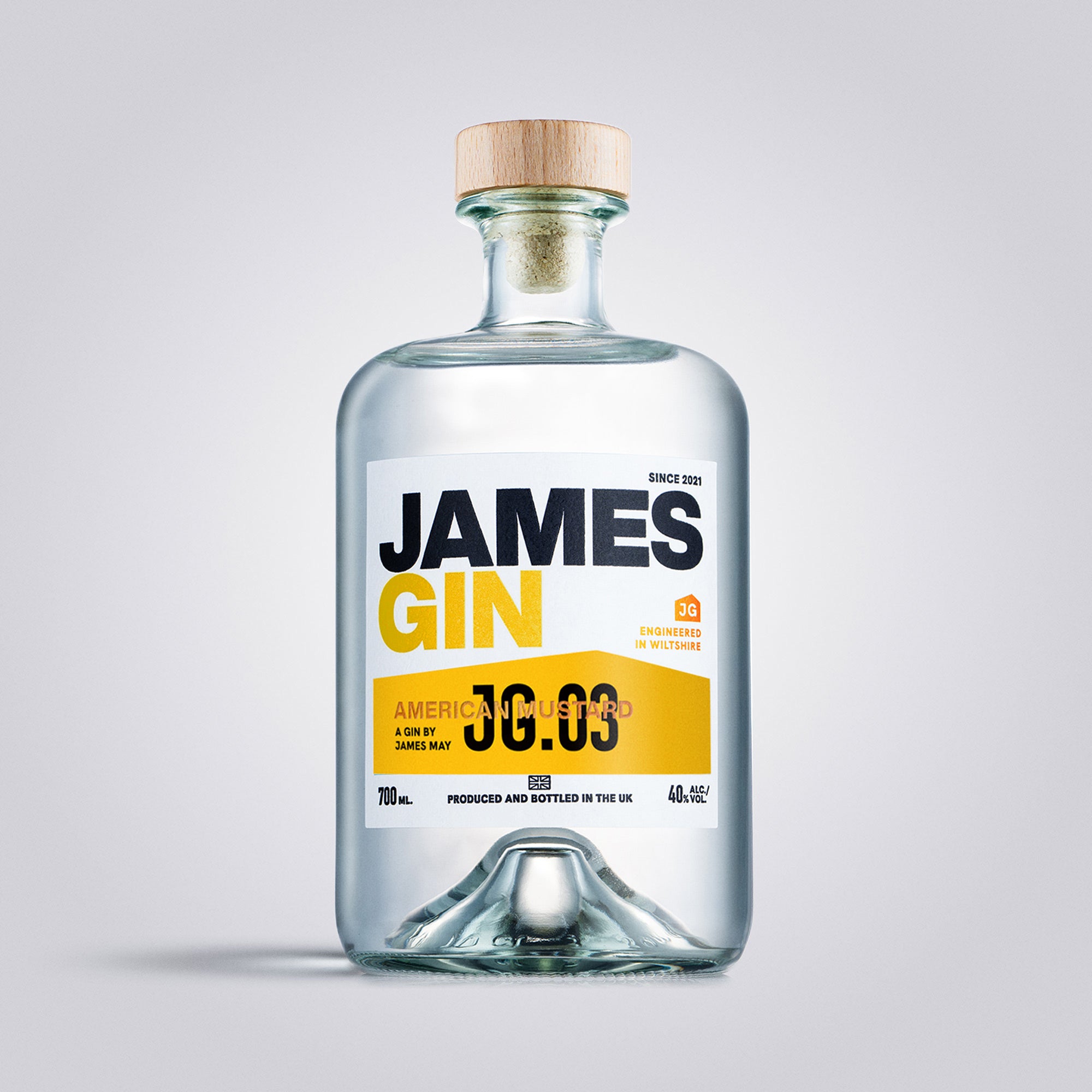 A clear glass bottle of James Gin with a label that reads 'JG.03 AMERICAN MUSTARD 40% ABV'.