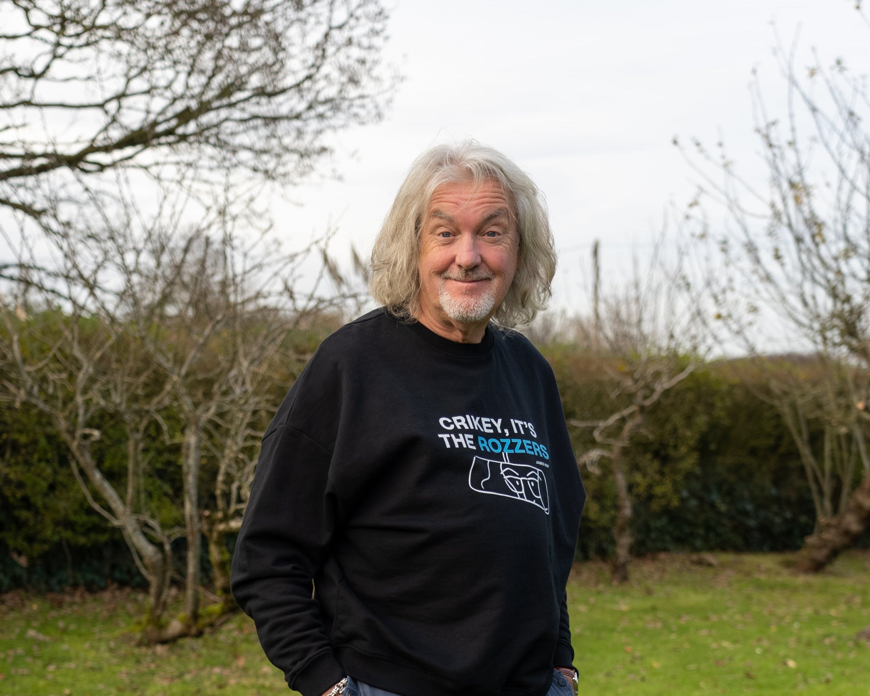 James May wearing his "crikey it's the rozzers" crewneck smiling with his eyebrows raised